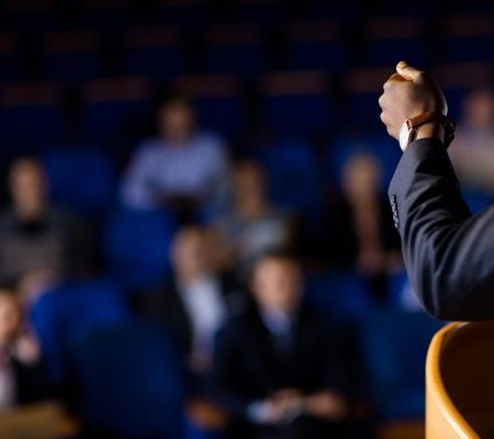 male-business-executive-giving-speech-scaled-600x400